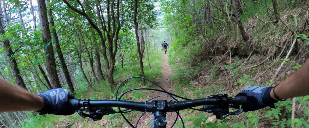 A mountain biker on a trail with a friend going thru a rocky path in the Cedar Creek Recreation Area in New Mexico.