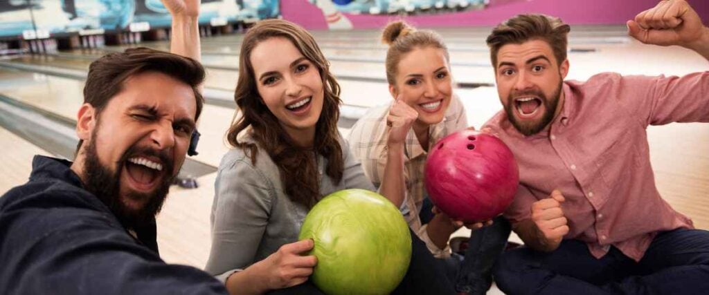 Two couples smiling while bowling. 