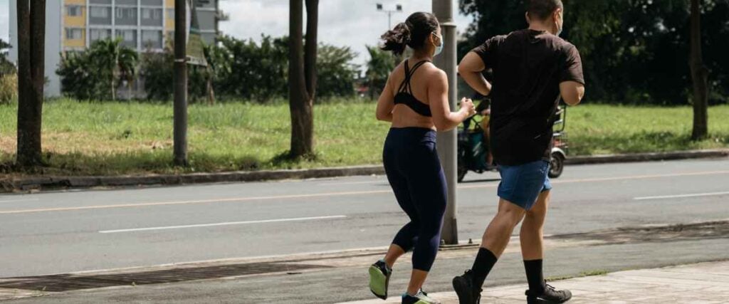 A couple running on a side walk during a warm day.