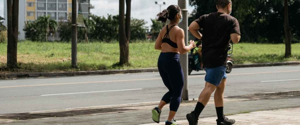 A couple running on a side walk during a warm day. 