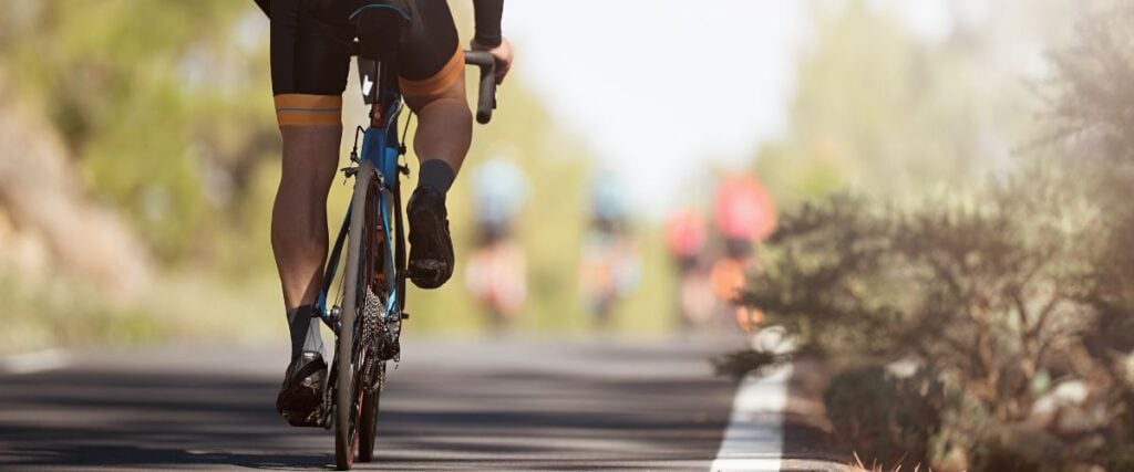 A male cyclists on the road towards his group of other cyclists ahead.