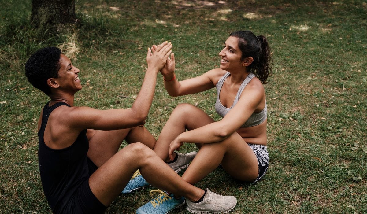 Two people high fiving in the park after a workout.