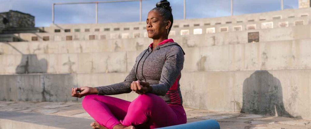 A woman meditating on a lake before her workout. 