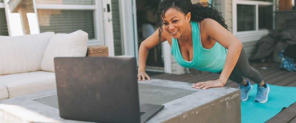 A woman doing her workout on our porch while watching her computer screen. 