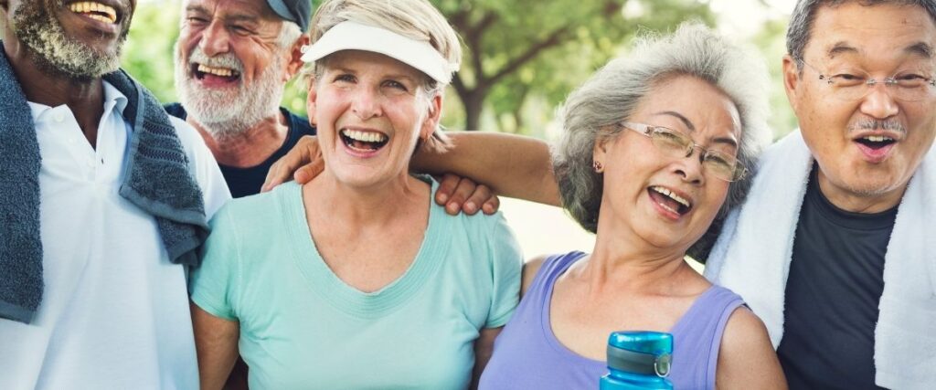 A group of older adults smiling in the camera laughing after their workout.