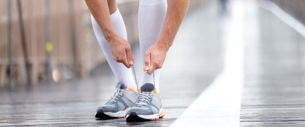 A runner tying his shoe on a bridge. 
