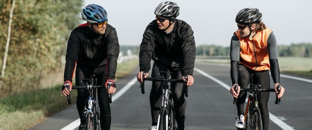 A group of male cyclists on a road talking to each other. 