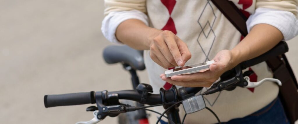 A man looking at his phone for his biking route to work. 