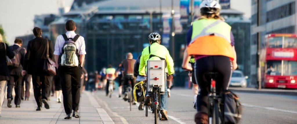 A view of commuters with an emphasis on two cyclists wearing bright neon colors.