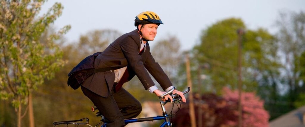 A man in a suit on his way to work on bike. 
