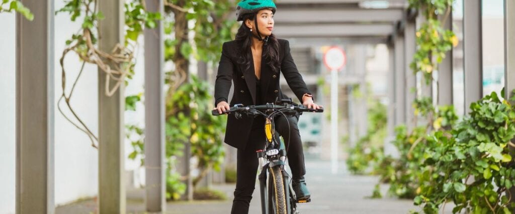 A woman in a suit on a bike on her way to work. 