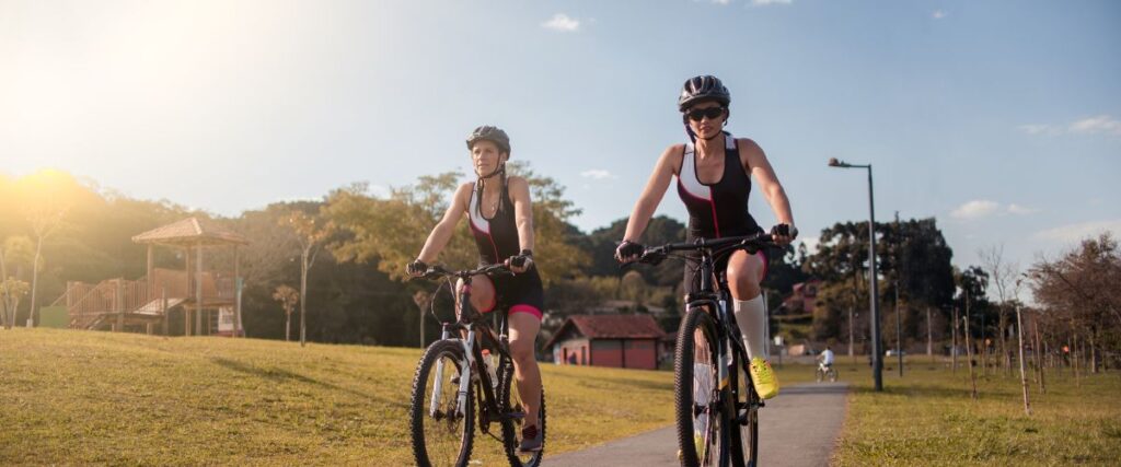 Two women cycling in a park. 