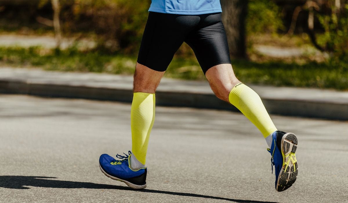 A man running with bright yellow compression socks on. 