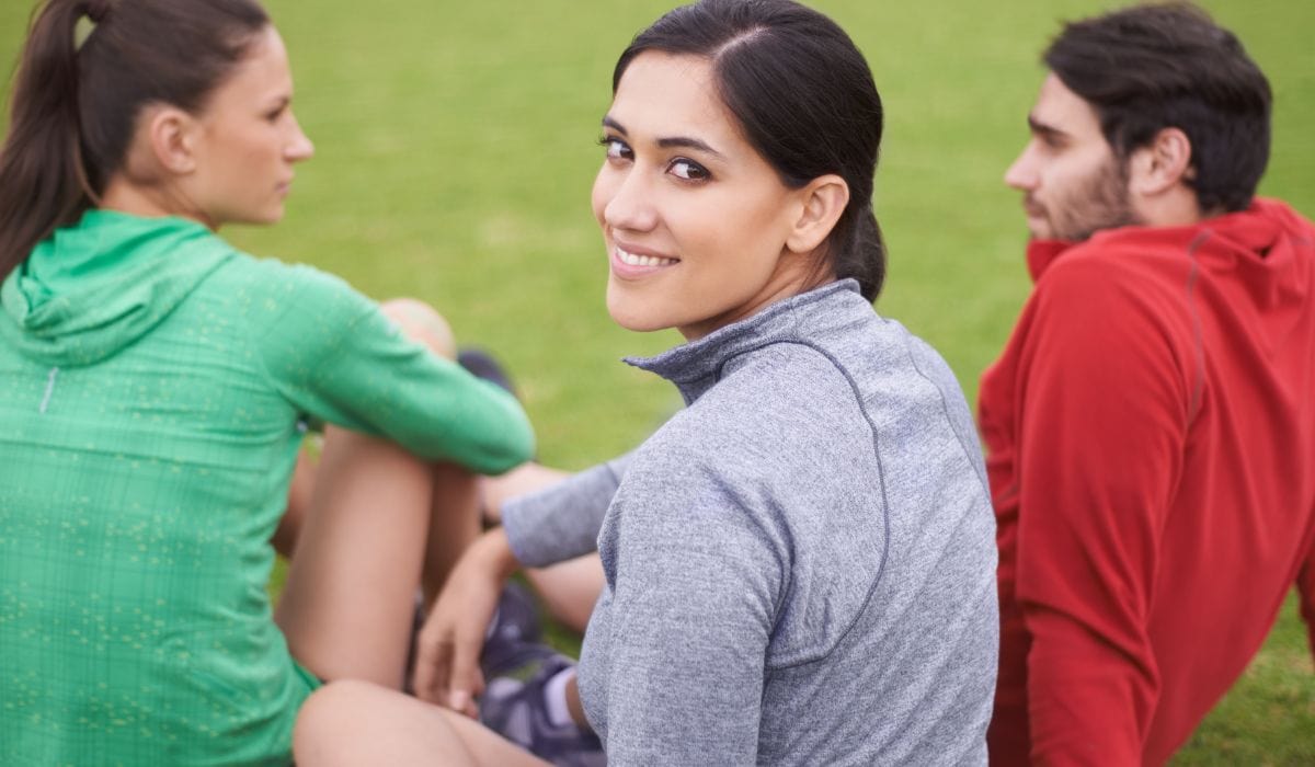 Woman looking at camera with her friends at a park.  