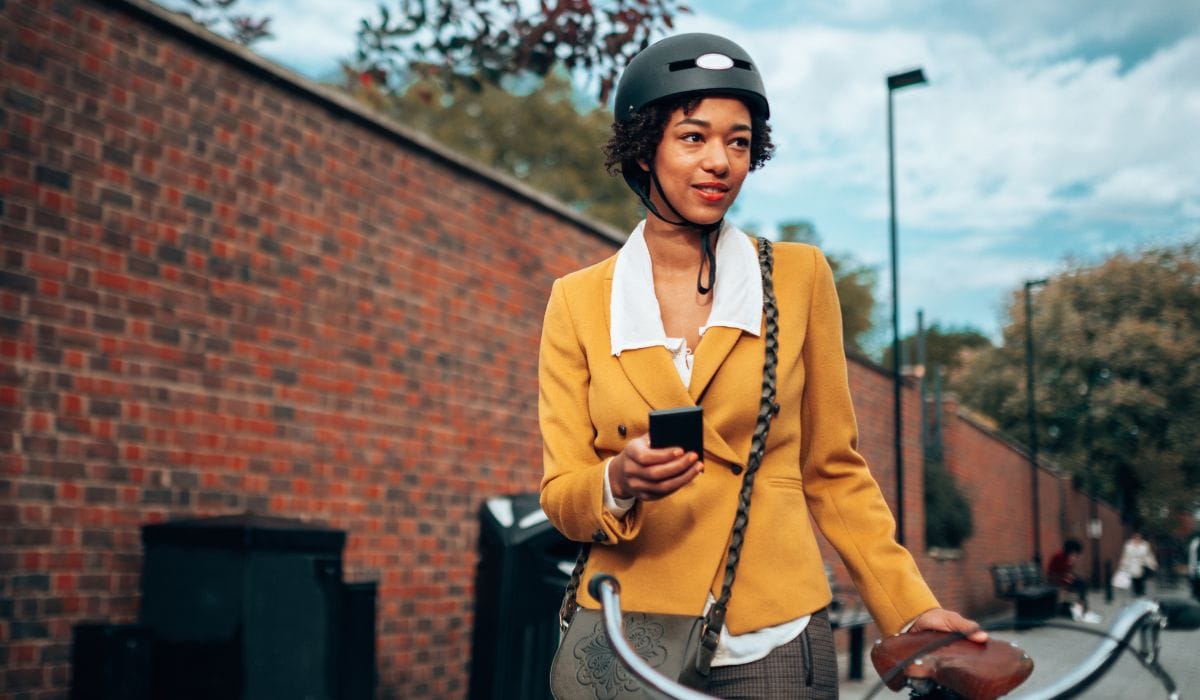 A woman wearing a helmet and suit on her way to work on her bike.