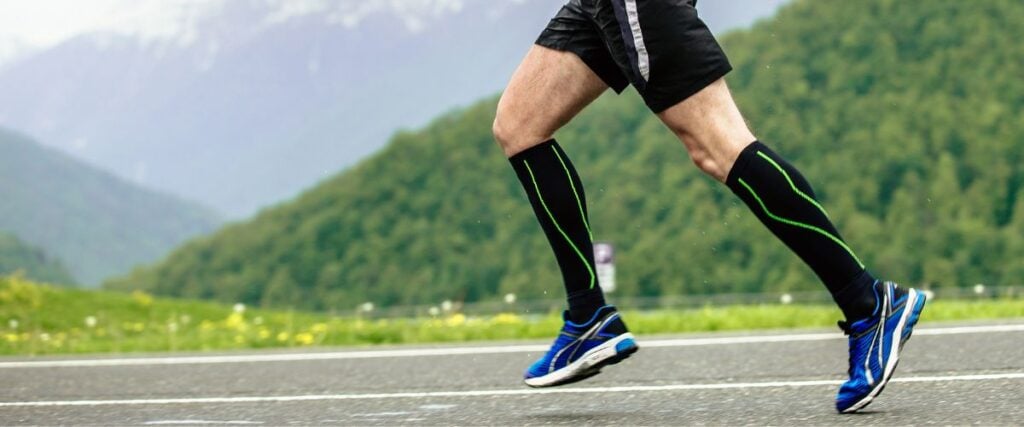 A man running on the road with compression socks. 