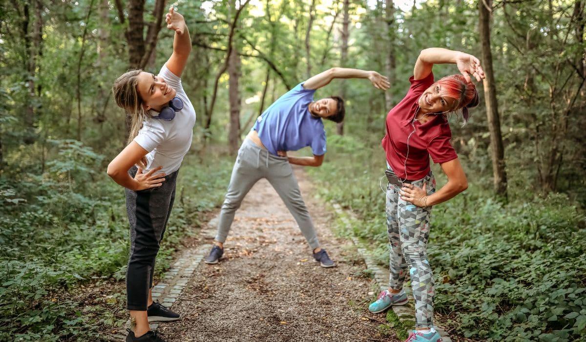 A group of runners stretching before their run in the woods. 