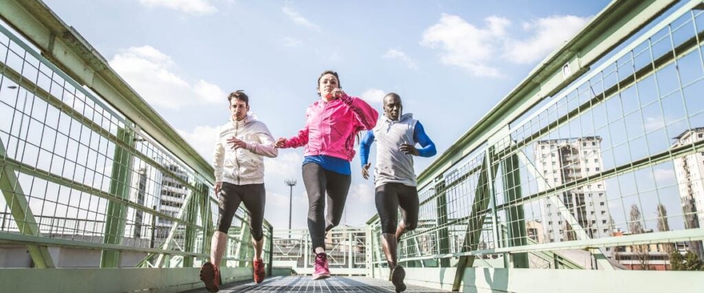 A group of runners going over a bridge together mid-run. 