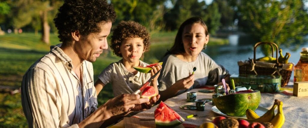 A family snaking a picnic with an array of healthy fruits and veggies. 