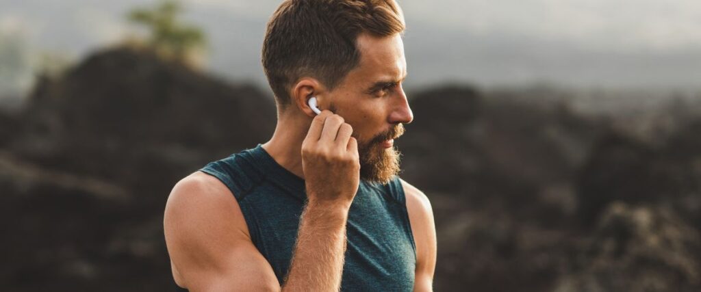 A male runner about to put in his wireless headphones before his workout. 