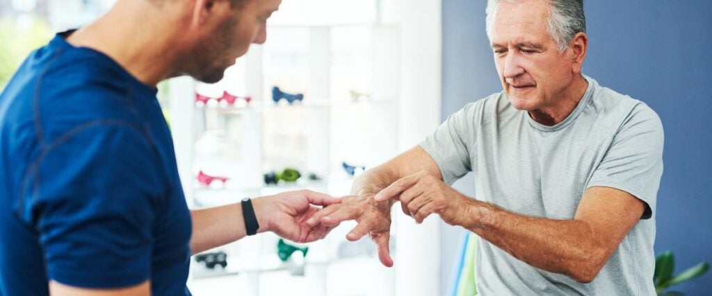 A man showing his hand to a physical therapists. 