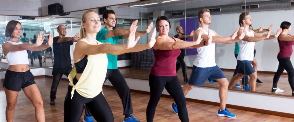A group of people at a gym taking a dance class together. 