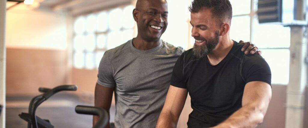 Two men at the gym laughing after a workout. 