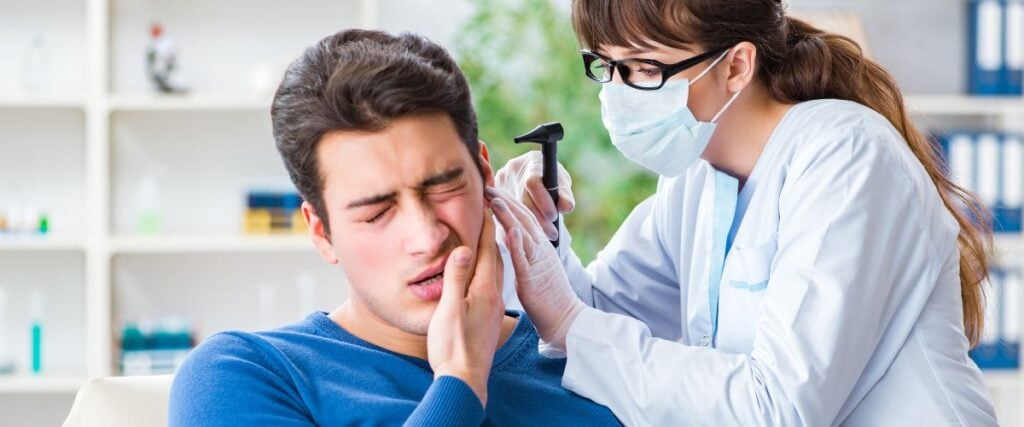 A man seeing an ear doctor holding his face. 