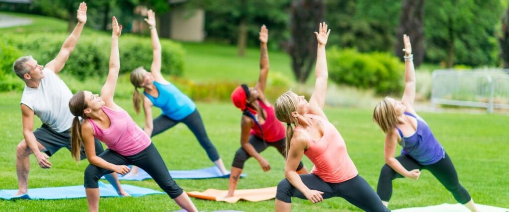 A group of people doing yoga in a park. 