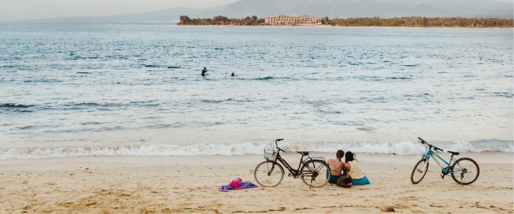 two friends take a break on the beach after cycling together