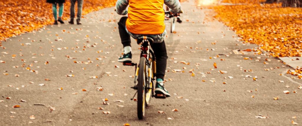 A little boy bikes along a scenic trail in autumn.