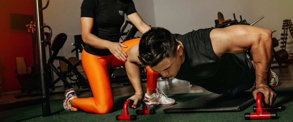 A coach helps her client perform HIIT (high intensity interval training) workouts.